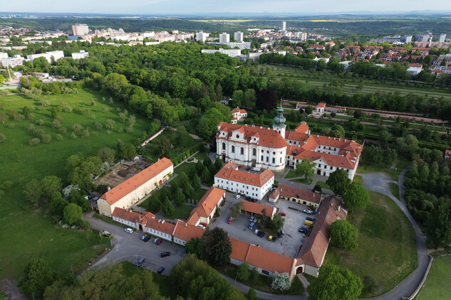 Areál Břevnovského kláštera, atypický pohled z ptačí perspektivy, na pozadí sídliště Petřiny a Červený Vrch. Zkoumaná plocha válečných hrobů leží vlevo za budovou sýpky (foto Egon Ditmar, 8. 5. 2025).